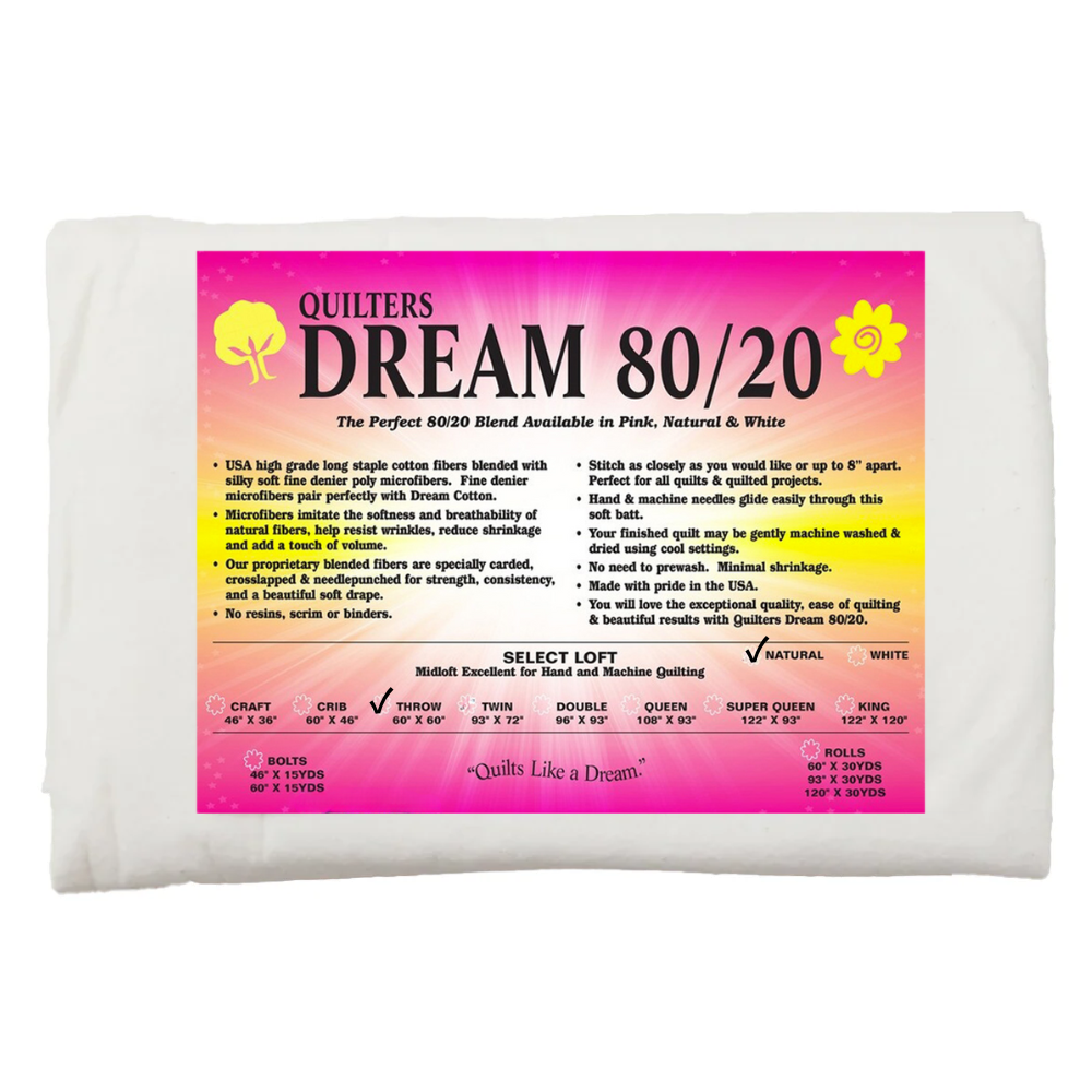 60" x 60" Mid Loft 80% Cotton & 20% Poly Batting Quilter's Dream in white, with a detailed label showing fiber content and sizing chartβideal for quiltingβset against a pink and yellow background.