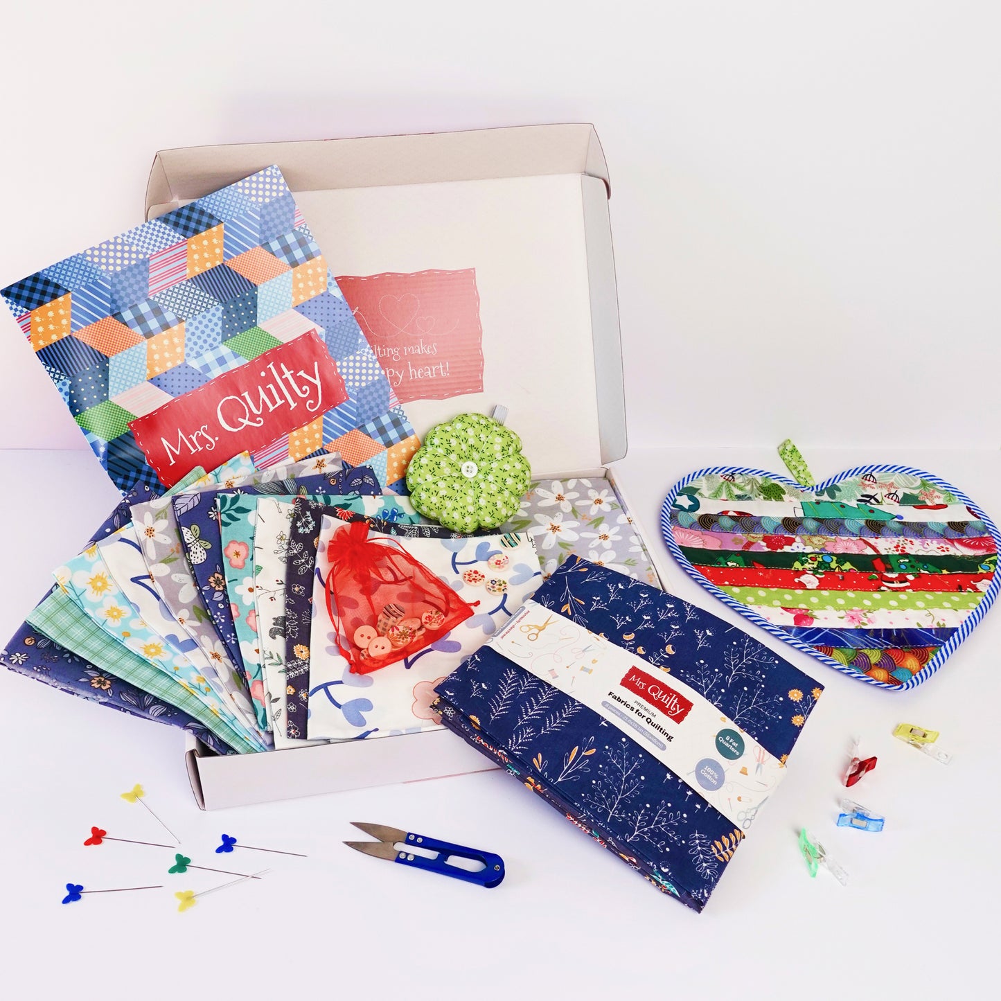 Product Name: 4th July Image Container. Includes fabric squares, a red pouch, a circular pin cushion with multicolored pins, a seam ripper, and a colorful quilted heart on a white background quilting kit.