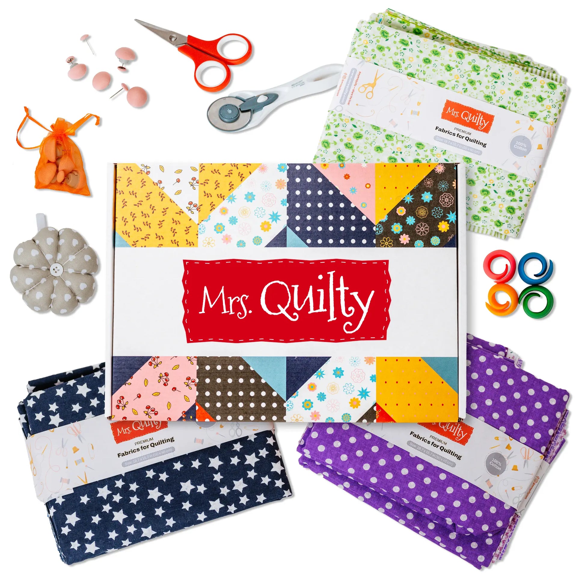 [3-Month Prepaid] Mrs Quilty Subscription Box includes colorful fabric squares, scissors, rotary cutter, pin cushion, spools of thread, and a needle pack arranged around the box.
