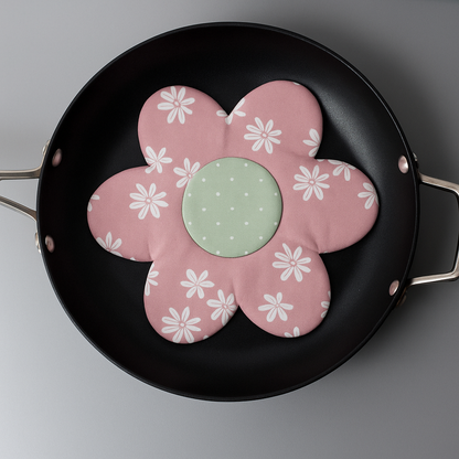 A black frying pan holds a pink, flower-shaped pan protector featuring white daisies and a green center—made using the Big Flower Pan Protector Downloadable PDF Quilt Pattern, perfect for beginner quilters.