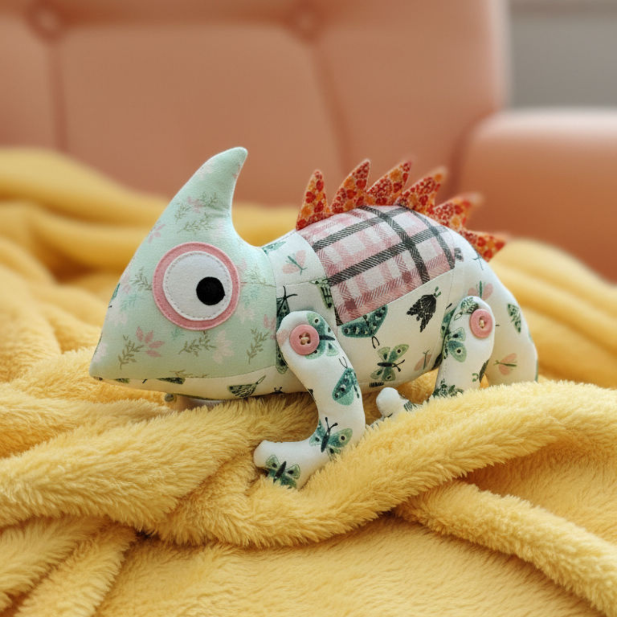 Stuffed dinosaur toy with floral and plaid patterns on a yellow blanket
