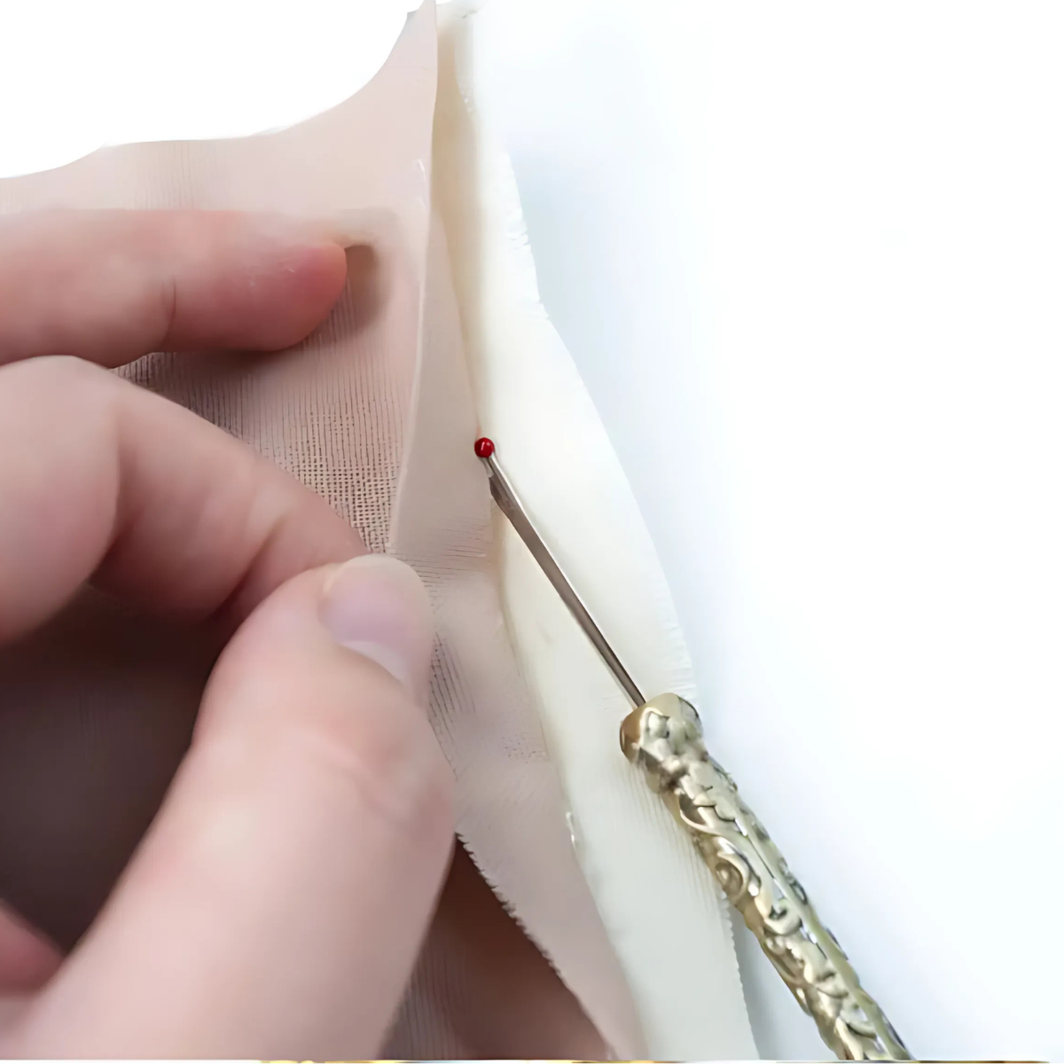 The Vintage Seam Ripper Set is used to remove stitches from light-colored fabric, with a hand holding the material steady for precise seam ripping.