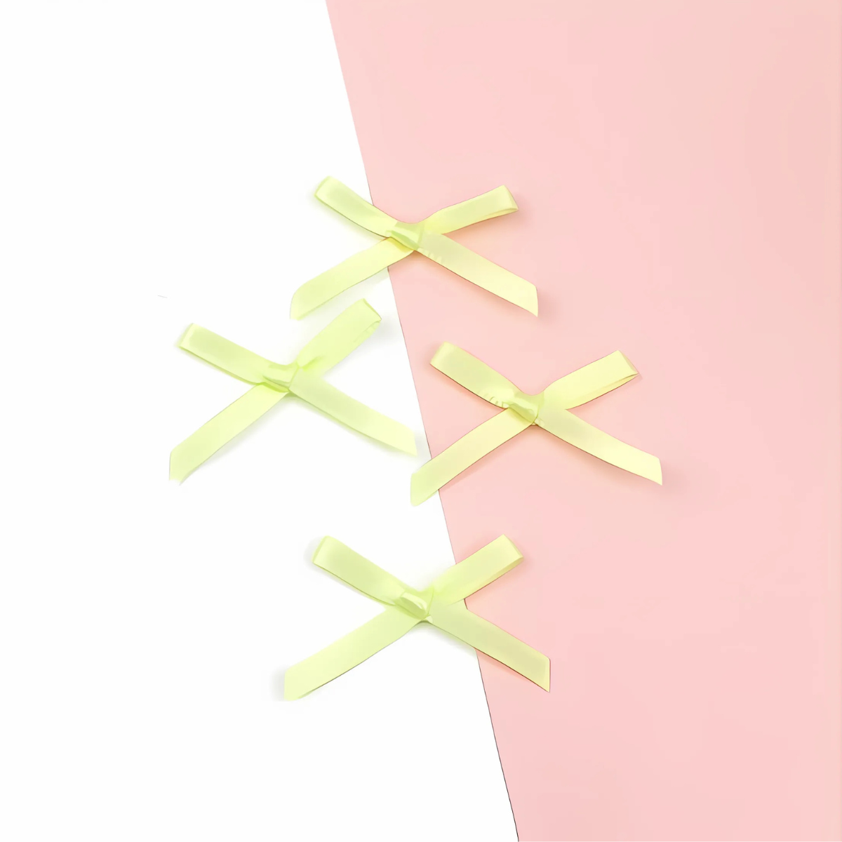 Five small bows from the Pastel Satin Ribbon Set, crafted from luxurious polyester, are displayed on a surface divided diagonally into white and pink halves.