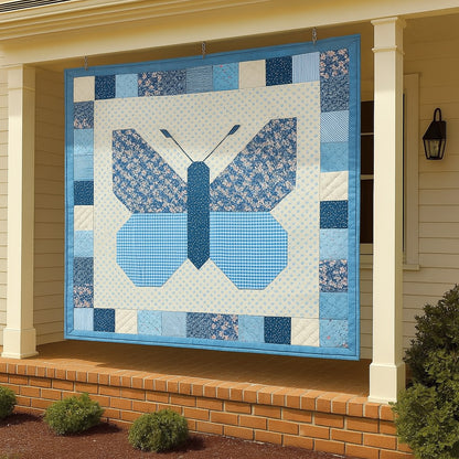 The Bundle of 14 Quilt Patterns, featuring beginner-friendly and unique designs like a large blue butterfly quilt, is displayed hanging on the porch of a house with white siding and brick steps.