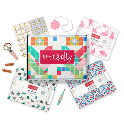 A handcrafted Wooden Sewing Box with Handle (Images54) sits on a white background, showcasing neat rows of colorful "Mrs. Quilty" fabric bundles, scissors, thread, and measuring tools.