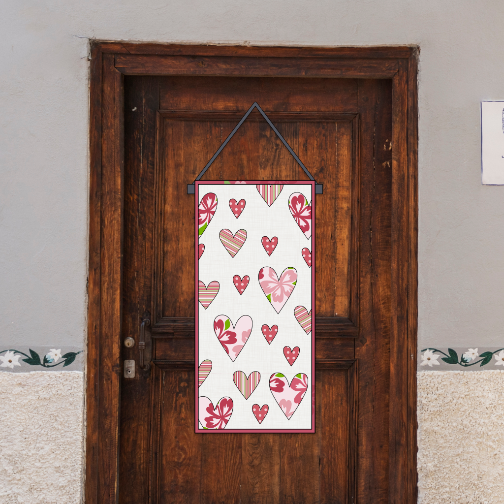 A wooden door displays a customizable Valentine's Day door hanger, created using the "Valentine’s Day Door Hanger Downloadable PDF Quilt Pattern," featuring a sign decorated with red and pink heart appliqués.