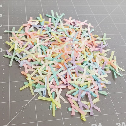 A set of small, pastel-colored satin ribbons from the Pastel Satin Ribbon Set is scattered on a gray cutting mat with measurement lines.