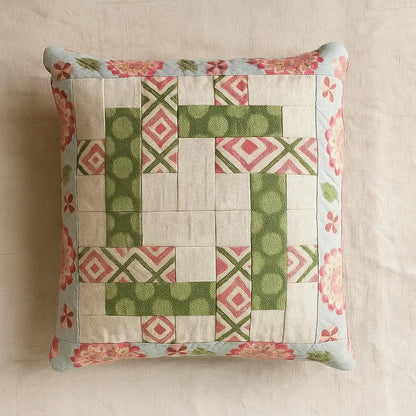 The Intertwined Pillow Case Downloadable PDF Quilt Pattern features green, pink, and cream geometric patchwork with a floral border on a neutral background—an intermediate-level design perfect for adding an accent to any space.