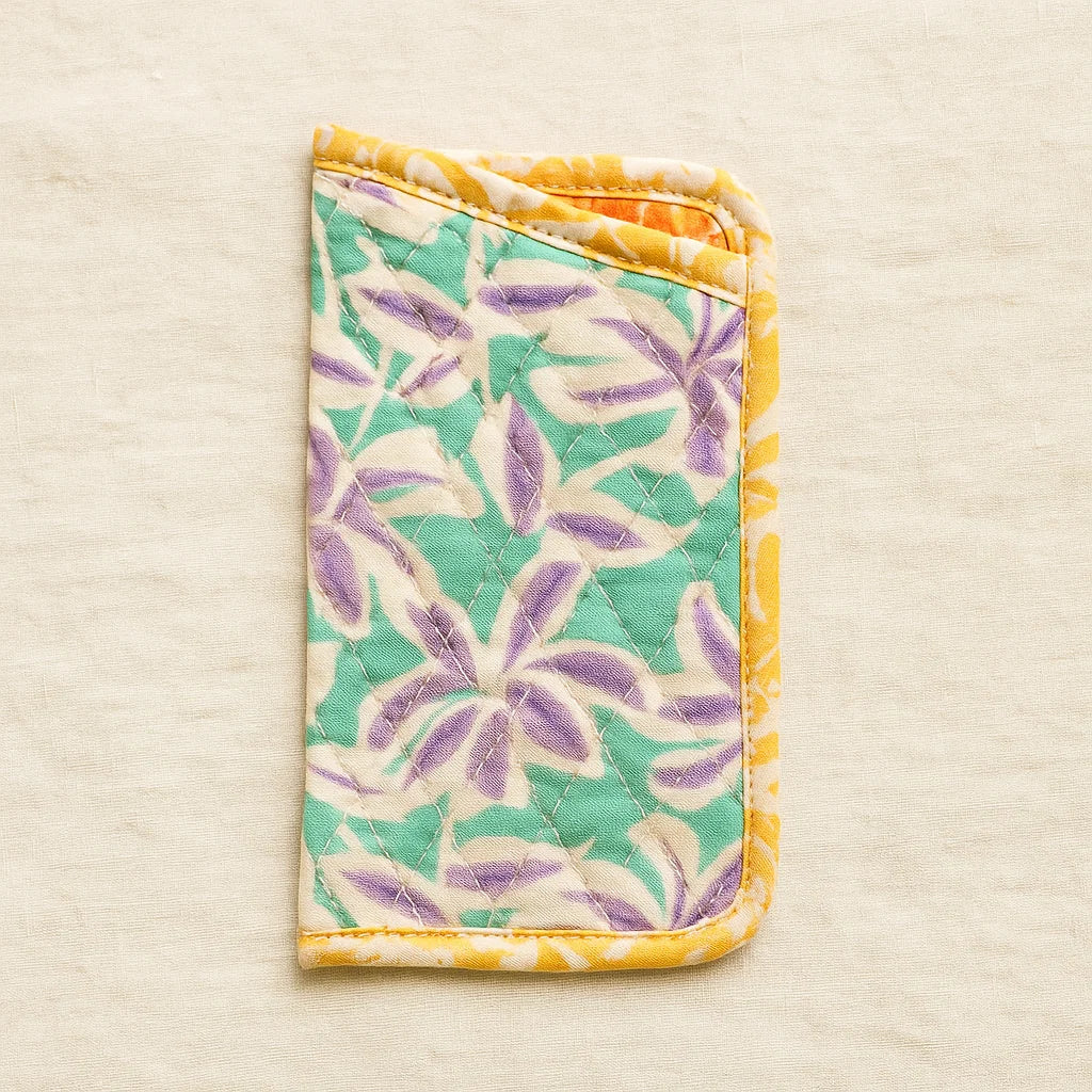 The Quilted Glasses Sleeve Downloadable PDF Quilt Pattern features a floral design in green, purple, and yellow—perfect for fans of beginner quilting patterns. Displayed on a neutral beige background.