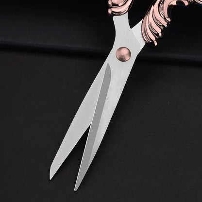 A close-up of Embroidery Scissors featuring stainless steel blades and ornate copper-colored handles, shown on a black surface.