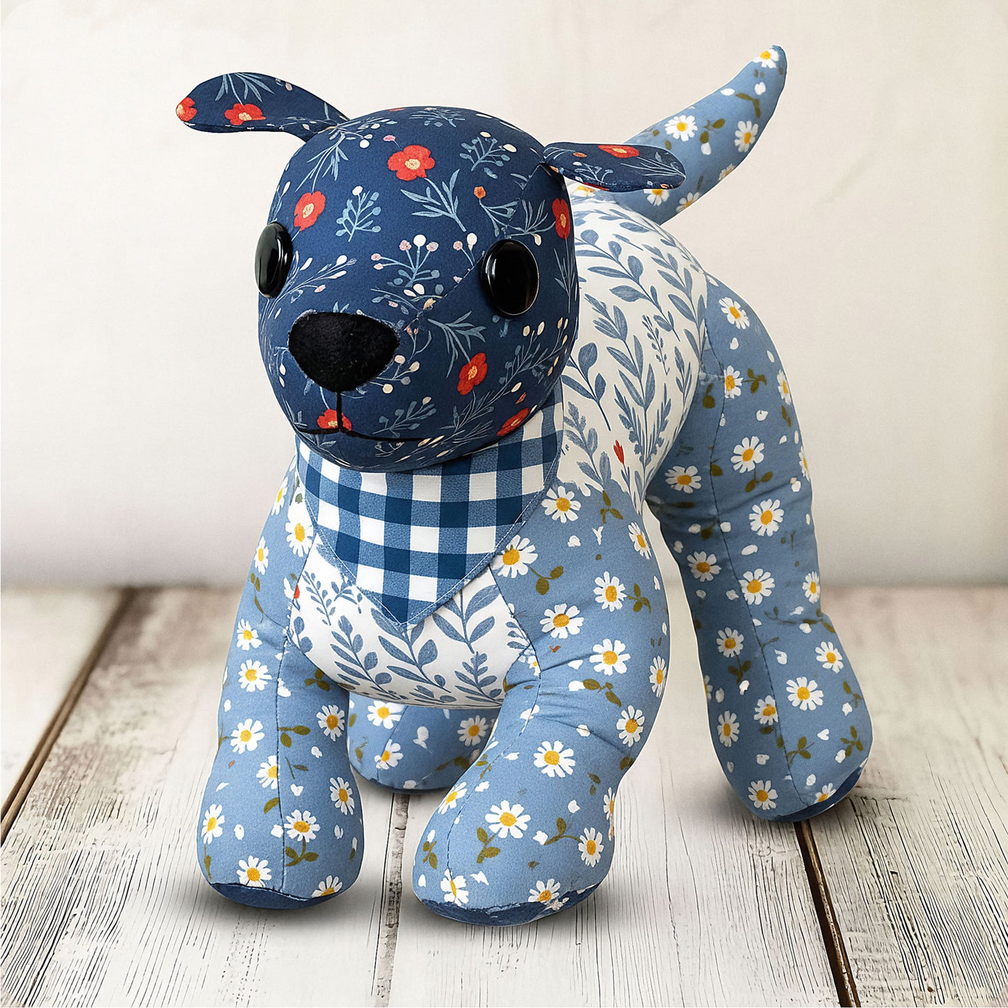 The Mrs. Quilty Plushies – Bundle of 14 Quilted Patterns includes charming designs like a handmade stuffed dog with floral and checkered blue prints, black button eyes, and a black nose—ideal inspiration for your own sewing projects.