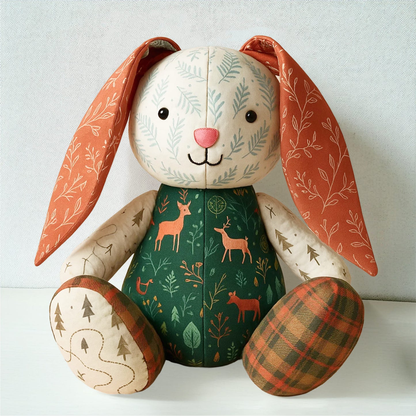 Mrs. Quilty Plushies – Bundle of 14 Quilted Patterns: Handmade stuffed bunny toy with deer, tree, and leaf fabrics sits upright against a plain background. Ideal for fans of handmade plush animals.