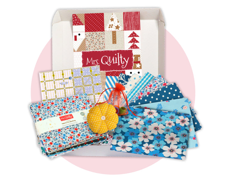 An open Mrs. Quilty box filled with coordinated fabrics and quilting supplies