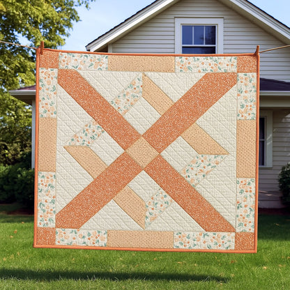 A square quilt featuring orange, beige, and floral designs hangs on a clothesline in front of a white house—showcasing the Bundle of 14 Quilt Patterns, ideal inspiration for beginner quilters.